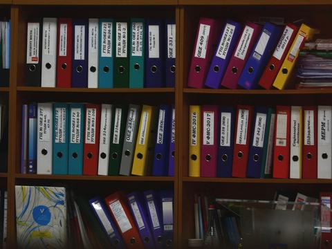 Labelled ring binders arranged on office shelves.