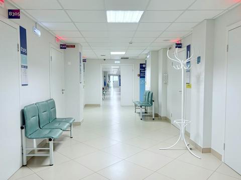 An empty, clean clinic corridor with waiting chairs.