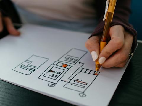 Hands sketching app wireframes on paper.